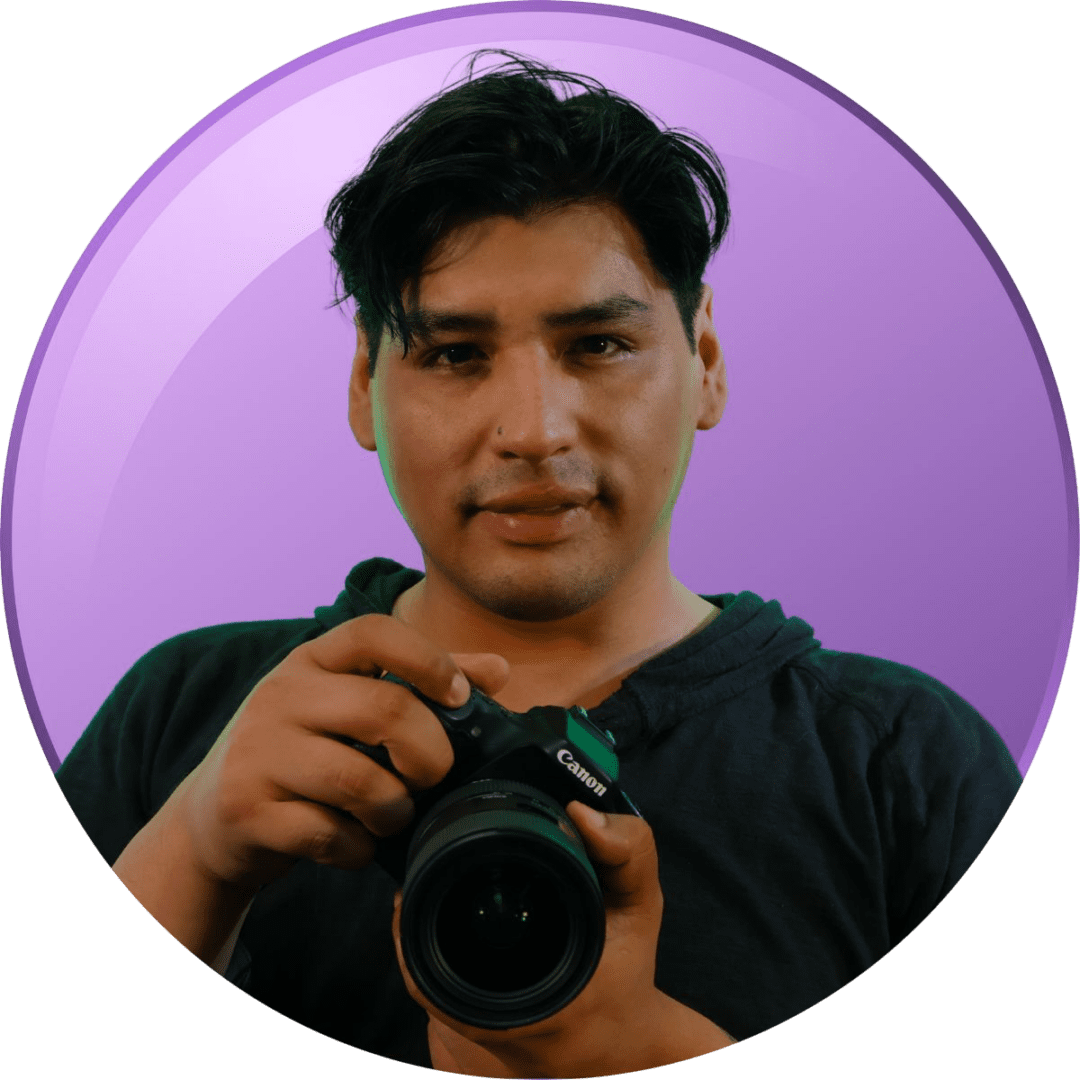 Man holding a camera against a purple background.