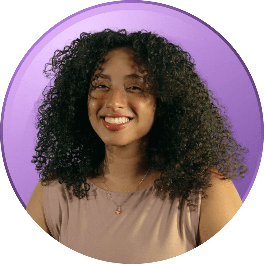 Smiling woman with curly hair against a purple background.