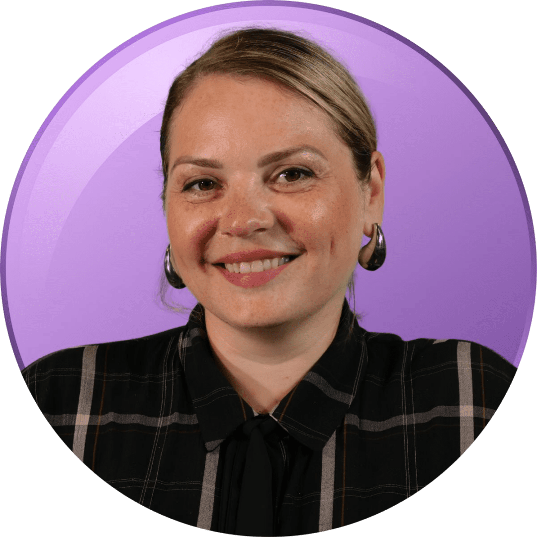 Smiling woman with a purple background and plaid shirt.