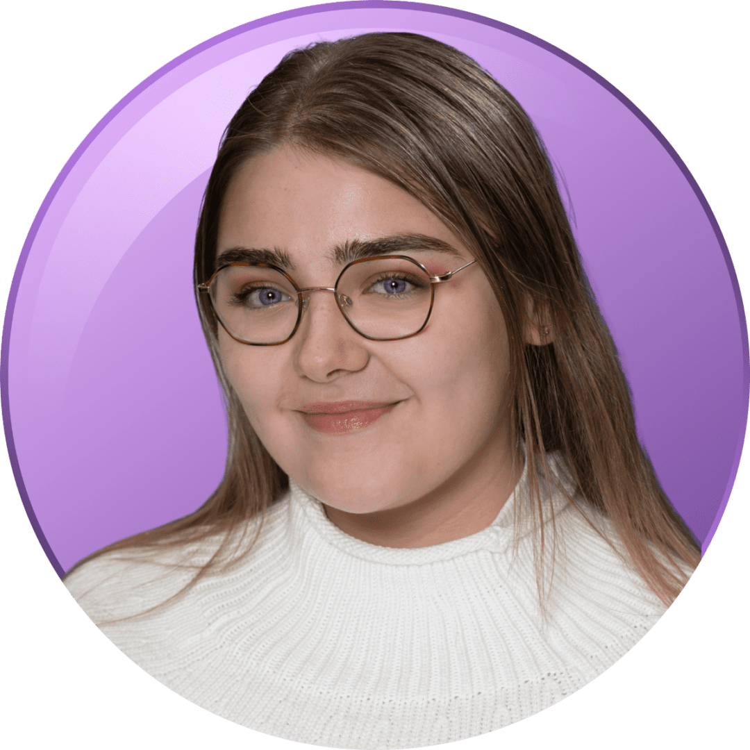 Young woman with glasses and a white sweater smiles gently.